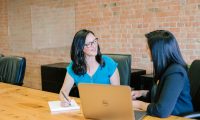 woman in teal t-shirt sitting beside woman in suit jacket